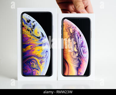 PARIS, FRANCE - SEP 25, 2018: Man hands presenting new iPhone Xs and Xs Max cardboard box compare before unboxing of smartphone against white background choosing Xs small version Stock Photo