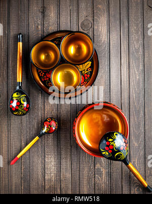 Wooden dishes, painted with floral ornament in the style of Khokhloma Russian wood art on the table Stock Photo