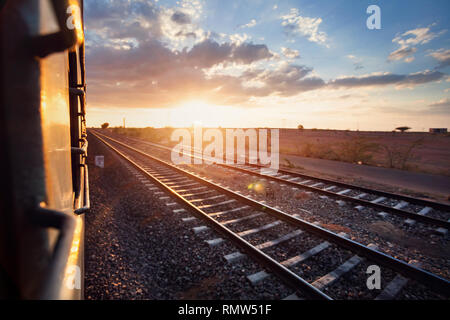 Train passing desert area at sunset sky beckgroung in Rajasthan, India Stock Photo