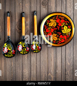 Wooden dishes, painted with floral ornament in the style of Khokhloma Russian wood art on the table Stock Photo