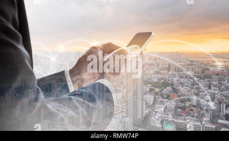 Double exposure, Businessman using mobile smart phone with cityscape in sunrise Stock Photo