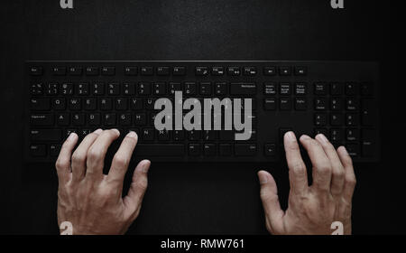 Top view, Hand typing computer keyboard on black background Stock Photo