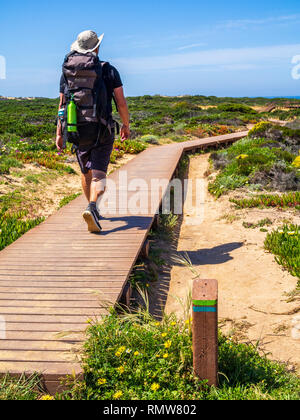 A hiker passes a striped signpost on the Fishermen's Trail between Zambujeira do Mar and Odeceixe in Portugal. The Fisherman's Trail is a four-day wal Stock Photo