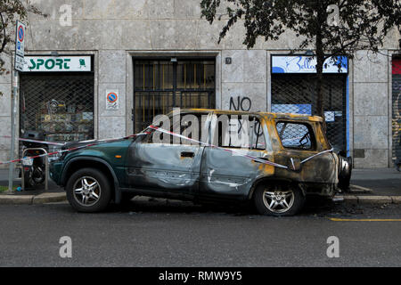 A burned out car on the street in Milan, Italy. The vehicle was burned in a riot protesting Milan hosting an Expo. Stock Photo