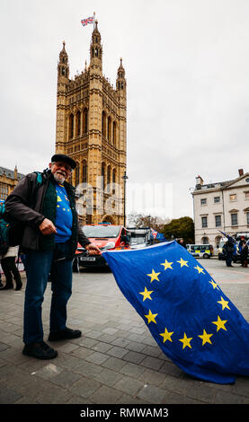 London, UK - Feb 11, 2019: Older man waves an EU and British flag protesting against Brexit in front of Westminster Palace, London, UK Stock Photo