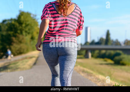 Rear view of young woman wearing sportswear running along river in a close up view Stock Photo