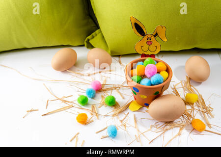 Easter eggs of different colors lying on the table next to the green  and the rabbit Stock Photo