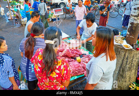 YANGON, MYANMAR - FEBRUARY 15, 2018: The street butchery in Chinatown market with queue of clients, on February 15 in Yangon. Stock Photo