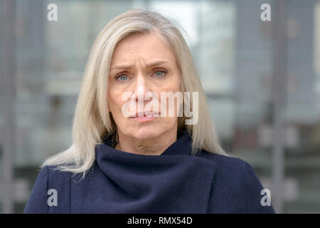 Puzzled troubled attractive middle-aged woman standing in an urban street frowning at the camera with an intent look Stock Photo