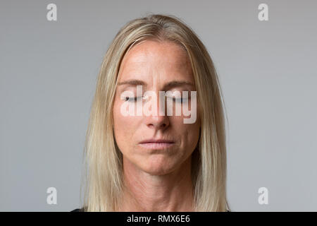 Closeup portrait of beautiful mature woman with closed eyes, light blue background. Stock Photo
