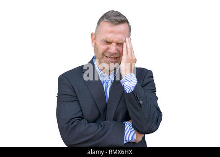 Stressed businessman, or suffering from a headache, standing with his hand to his temple grimacing against white background Stock Photo