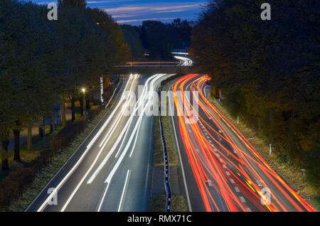 Traffic driving on a freeway at night in a long exposure with light trails of the headlights and tail lights winding away into the distance viewed fro Stock Photo