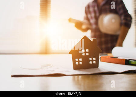 Real estate home concept, wood house on table with engineer standing background Stock Photo