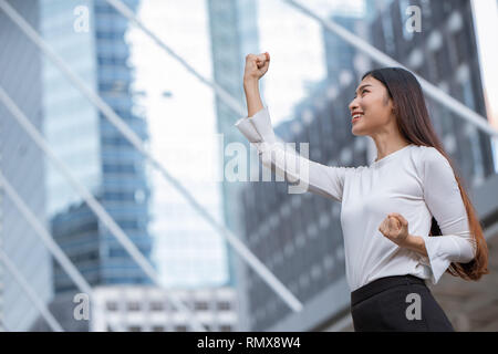 women rise her hand for business winner success concept with office building background. Stock Photo