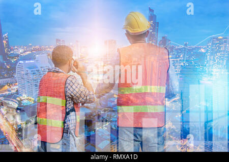 exposure engineers looking blue print and talking on radio with night city background Stock Photo