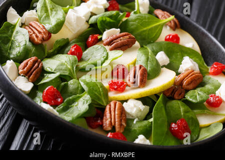 Fresh salad of pears, spinach, pecans, goat cheese and dried cherries close-up on a plate on the table. horizontal Stock Photo