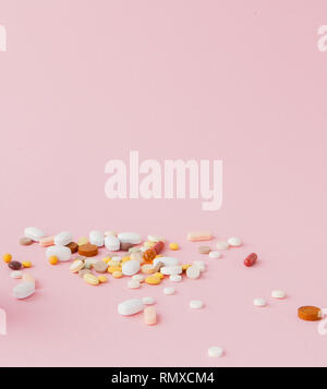 group of capsules and pills in different colors and shape isolated on pink background. Stock Photo