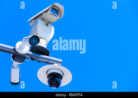 Few closed-circuit television cameras mounted on one pole under blue sky Stock Photo