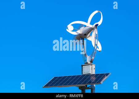 Small white wind turbine and solar battery panel over blue sky background Stock Photo