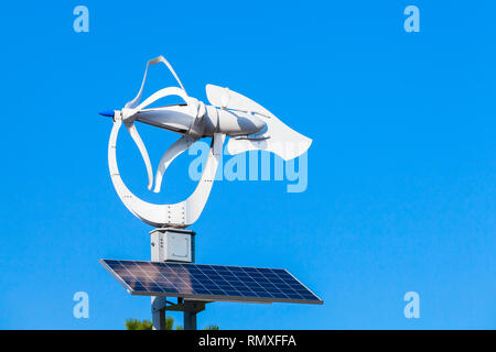 Small wind turbine with solar battery panel over blue sky background Stock Photo