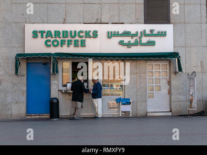 MEDINA, SAUDI ARABIA-CIRCA 2016 : Two Muslim men buy hot drinks at Starbucks Coffee outlet located just outside Nabawi Mosque in Medina, Saudi Arabia. Stock Photo