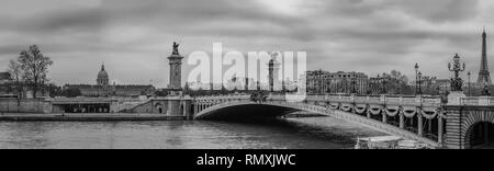 Moody cityscape panorama with Pont Alexandre III bridge, Seine river and Eiffel Tower in Paris, France in black and white treatment Stock Photo