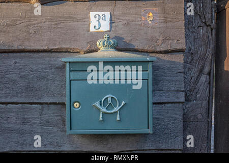 An old, rusty dutch mailbox hangs on the wall of an abandoned wooden house - Image Stock Photo