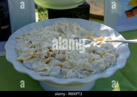 Originally cooked delicious dumplings with sour cream in a white plate on the background of the table. The concept of delicious and healthy food. Stock Photo