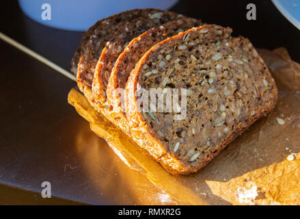 Originally baked delicious rye bread with sunflower seeds inside against the table. The concept of delicious and healthy food. Stock Photo