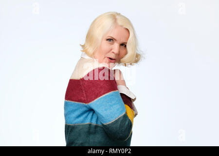 Senior european woman hides something in her hands and looks warily forward Stock Photo