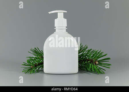white blank perfume dispenser bottle with pine tree branch on gray background Stock Photo