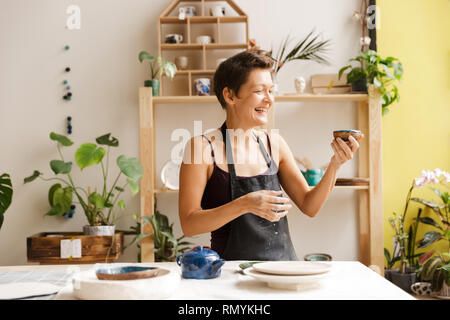 Woman potter drinking tea at the workshop Stock Photo