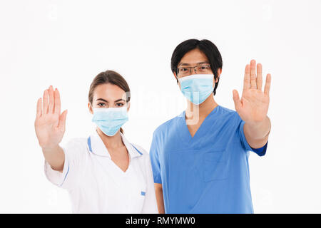 Confident doctors couple wearing uniform standing isolated over white background, showing stop gesture Stock Photo