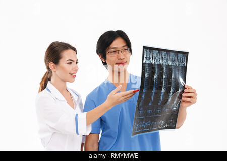 Confident doctors couple wearing uniform standing isolated over white background, examining x-ray photograph Stock Photo