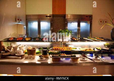 Japanese food and Sushi bar thai style many variety topping at buffet food line in restaurant for people dining dinner at Hotel in night time in Bangk Stock Photo
