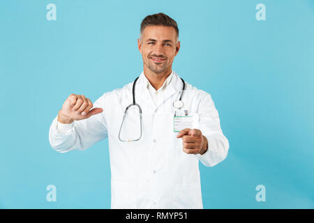 Confident man doctor wearing unifrom standing isolated over blue background, pointing at himself Stock Photo
