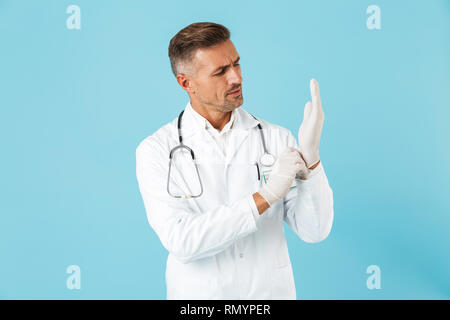 Image of a handsome mature man doctor posing isolated over blue wall background. Stock Photo