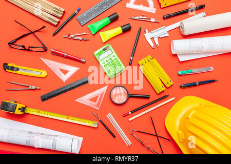Architect engineer equipment, construction site office desk. Project blueprints, hard hat and engineering tools on orange color, top view Stock Photo