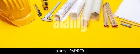 Architect engineer workplace, construction site desk. Project blueprints, hard hat and engineering tools on yellow, banner Stock Photo