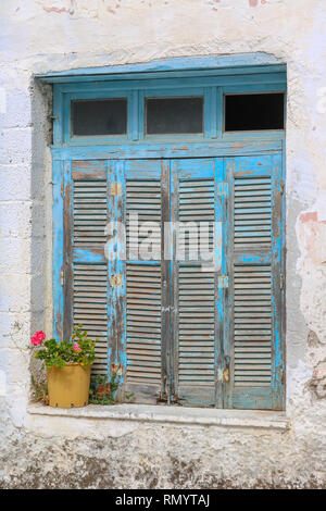 closed shutters at an old window with flowers, Paros, Greece Stock Photo