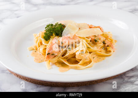 Delicious salmon pasta dish, tagliatelle noodles with Parmesan and parsley. Stock Photo