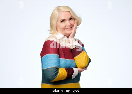 Senior caucasian woman with blonde hair in colored sweater smiling Stock Photo