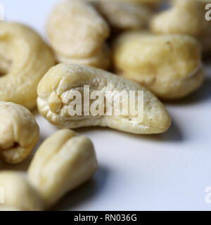 Natural, organic cashew nuts in a closeup photo. Photographed on top of a white table. Delicious and healthy nuts full of nutrients, good fatty acids. Stock Photo