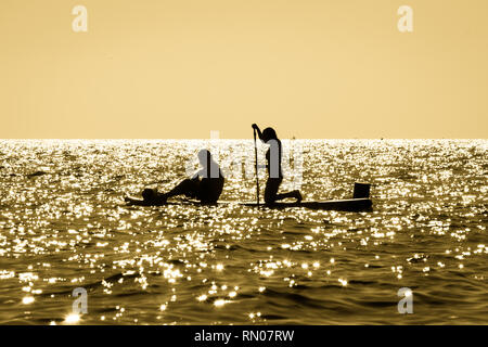 Picture of a Silhouette of a young couple paddling on a surf at sunset in Maro, Andalusia, Spain.