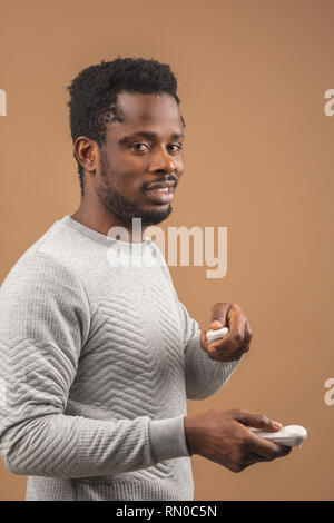 Dark-skinned millennial tourist in casual clothing wearing glasses with head-mounted display for smart phone, operating with controllers in hands, doi Stock Photo