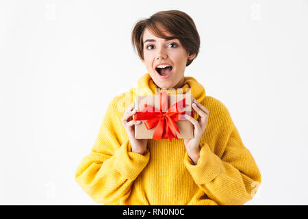 Happy cheerful girl wearing hoodie standing isolated over white background, holding gift box Stock Photo