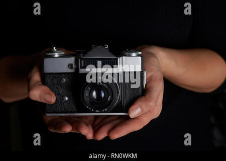 Love for photography, creativity.Creativities. Old film camera in hands on black background. Monochrome Stock Photo
