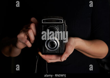 Love for photography, creativity.Creativities. Old film camera in hands on black background. Monochrome Stock Photo