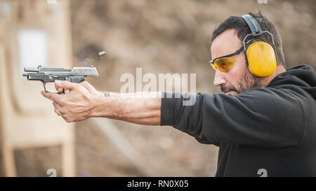Detail view of shooter holding gun and training tactical shooting, close up. Shooting range Stock Photo