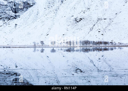 Snowy reflections with trees in Loch Achtriochtan, Glencoe, Scottish Highlands, Scotland UK in January Stock Photo